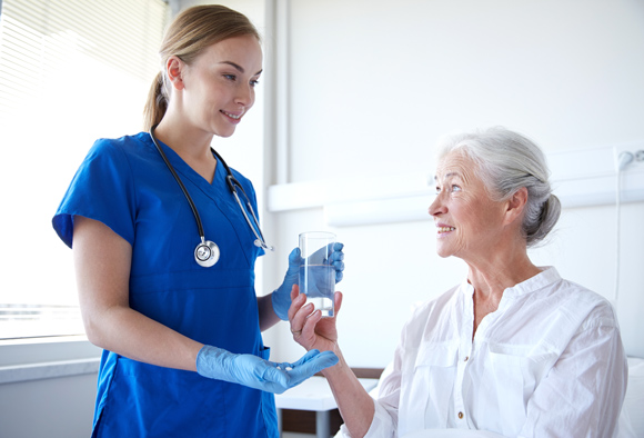 healthcare professional offering water to elderly patient in hospital smiling and caring interaction hydration support