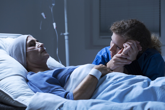 woman in hospital bed with serious illness while another woman comforts her in emotional moment